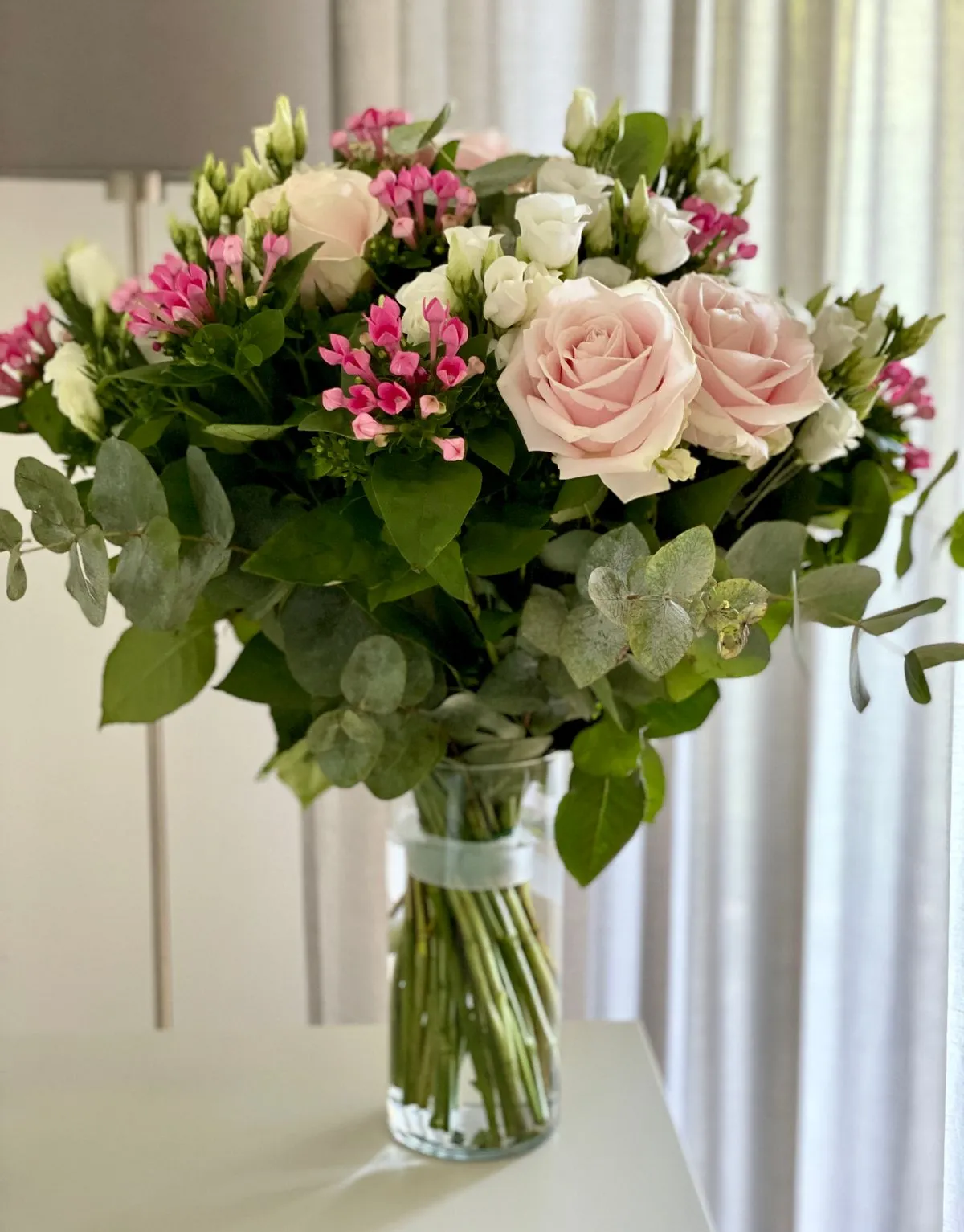 Cam vazoda karışık buket: pembe güller, beyaz lisianthus ve okaliptüs